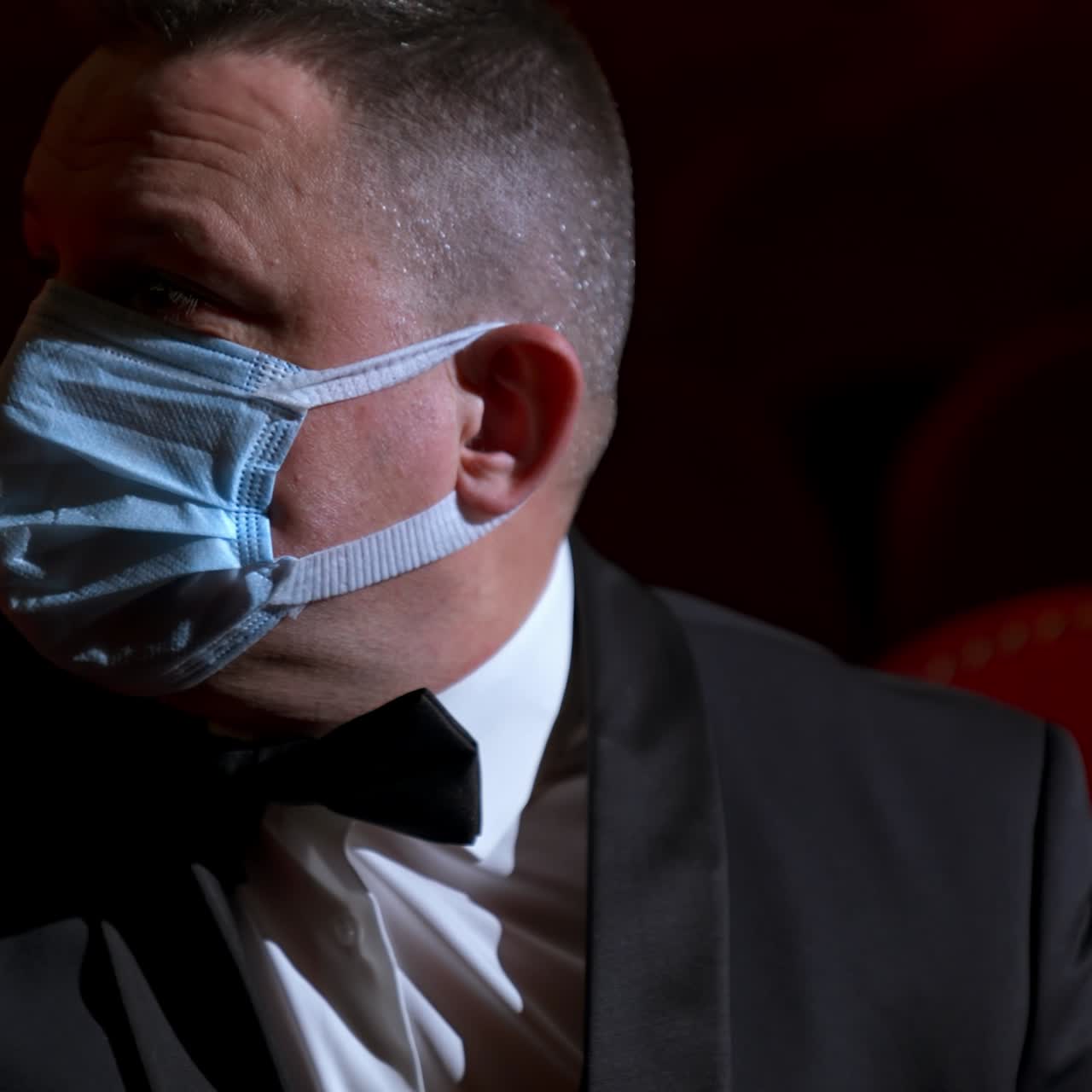 Lonely and sad visitor sits in empty theater hall alone. Person sits on a red chair during pandemic