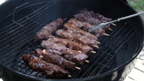 convertir kebabs de carne de res y cerdo marinados en una parrilla usando pinzas sobre un fuego abierto
