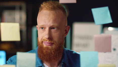 Smiling-business-man-enjoying-good-job-near-stickers-board-in-modern-office.