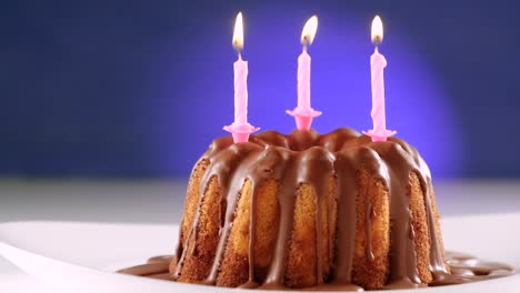 burning pink birthday candles on marble cake with chocolate nougat icing