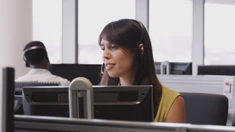 businesswoman wearing telephone headset talking to caller in customer services department