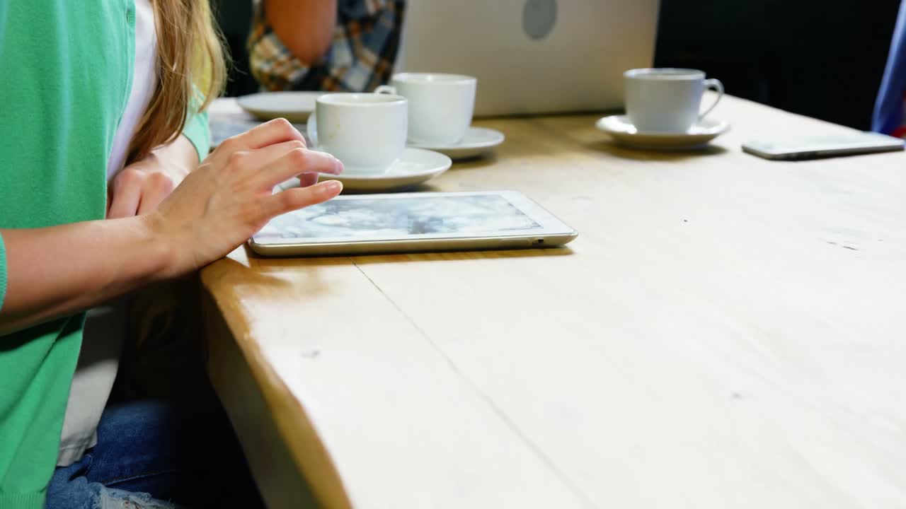 mujer usando una tableta digital mientras toma café