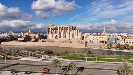 ascending drone shot showing traffic on highway and famous cathedral of palma de mallorca in background