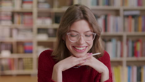 a young beautiful female student smiles into the camera while learning in the library—close-up shot