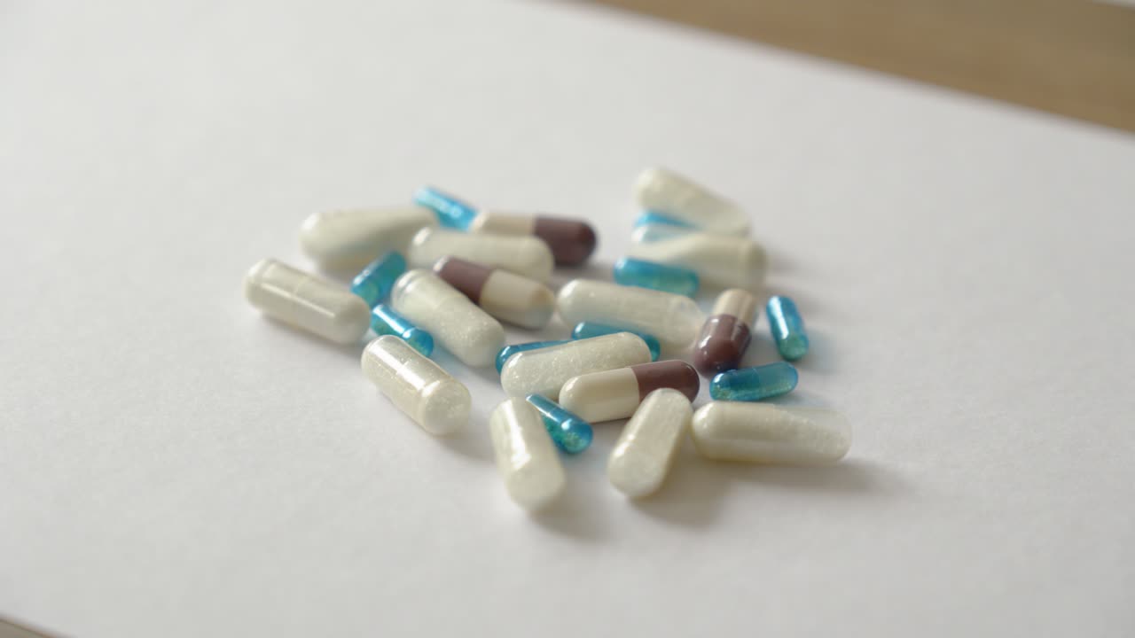 Various coloured and white medicine and drug capsules in a group on a table