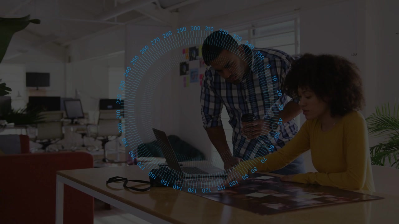 Woman tapping printed layouts and man leaning, pointing to laptop as HUD rotates, finalizing design