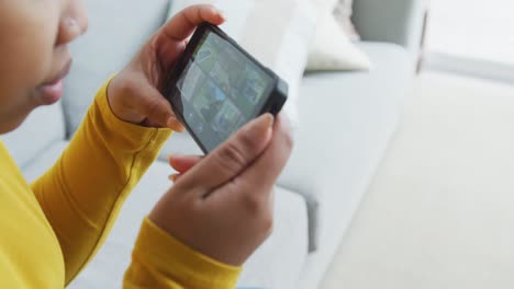 Happy-african-american-plus-size-woman-sitting-on-sofa,-using-smartphone-in-living-room