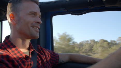 Young-man-driving-in-an-open-top-car-in-Summer,-close-up