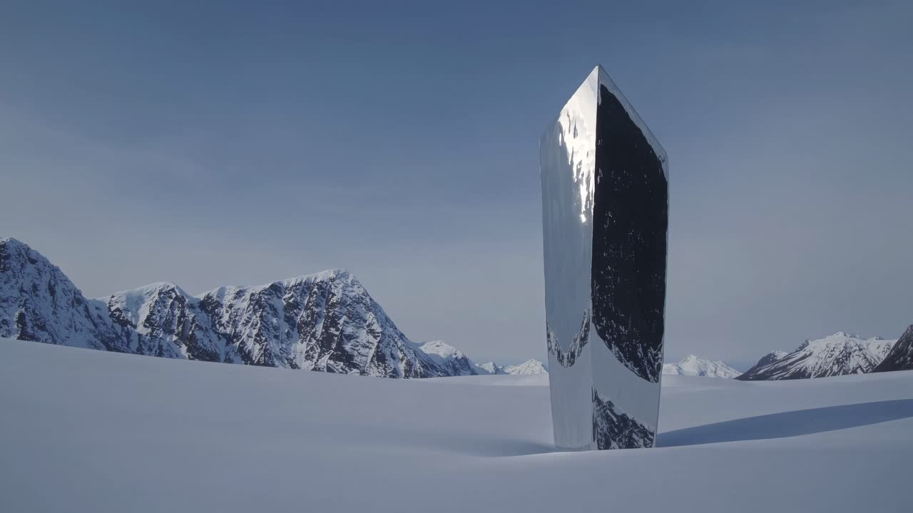 A mysterious monolith stands in a snowy landscape with mountains in the background