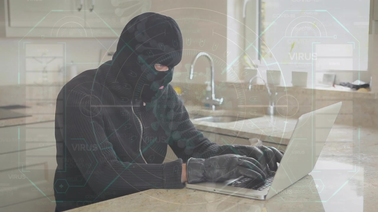 Włamywacz hakuje laptopa w kuchni.