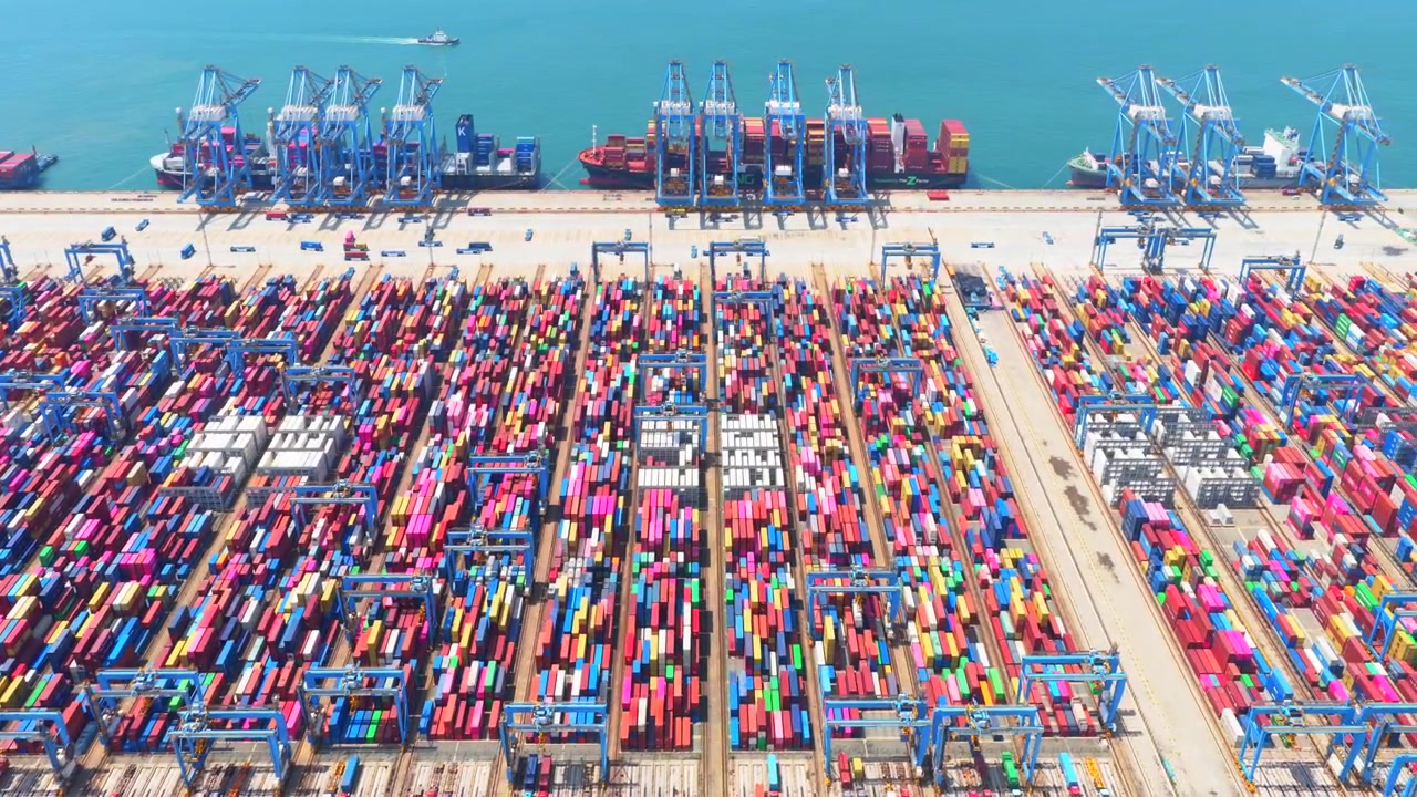 Aerial drone view of Qingdao fully automated smart container port, unmanned intelligent dock with automated cranes and container stacks for global shipping logistics