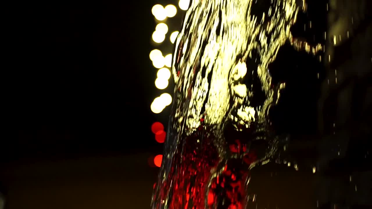 Slow Motion Water being lit by Red and Yellow Light