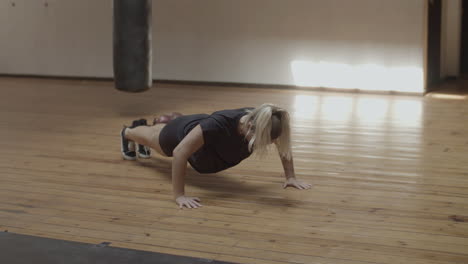 long shot of young woman doing push-ups in practice room