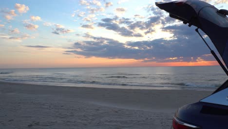 Sonnenuntergang-über-Dem-Meer-Mit-Einem-Blauen-Fließheckauto-Im-Vordergrund