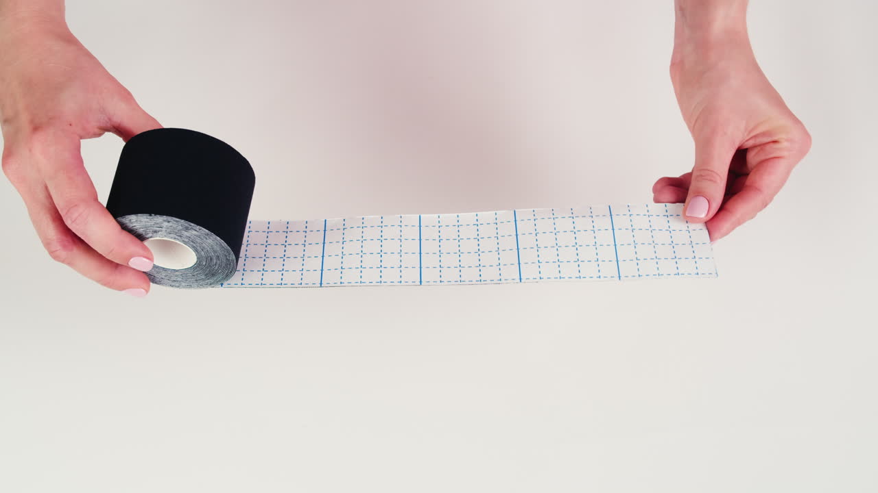 Kinesiology medical taping, doctor Physical therapist applying elastic surgical tape to patient body, treating injured knee young athlete.Post traumatic rehabilitation, sport physical therapy recovery