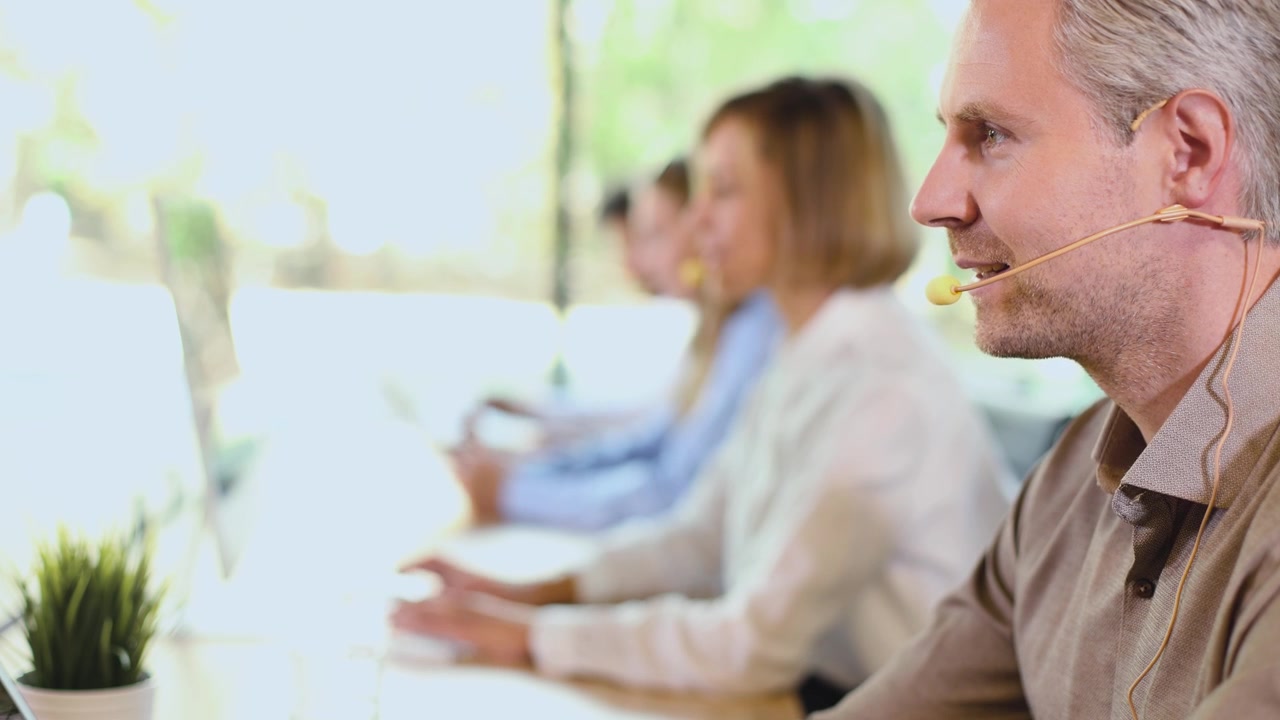 Uomo che parla in cuffia mentre lavora in un call center