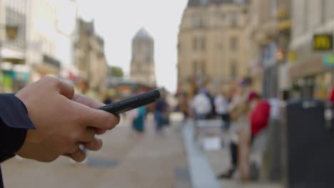 Schwenkaufnahme-Eines-Mannes,-Der-In-Einer-Belebten-Straße-In-Oxford-Eine-SMS-Auf-Dem-Handy-Schreibt?