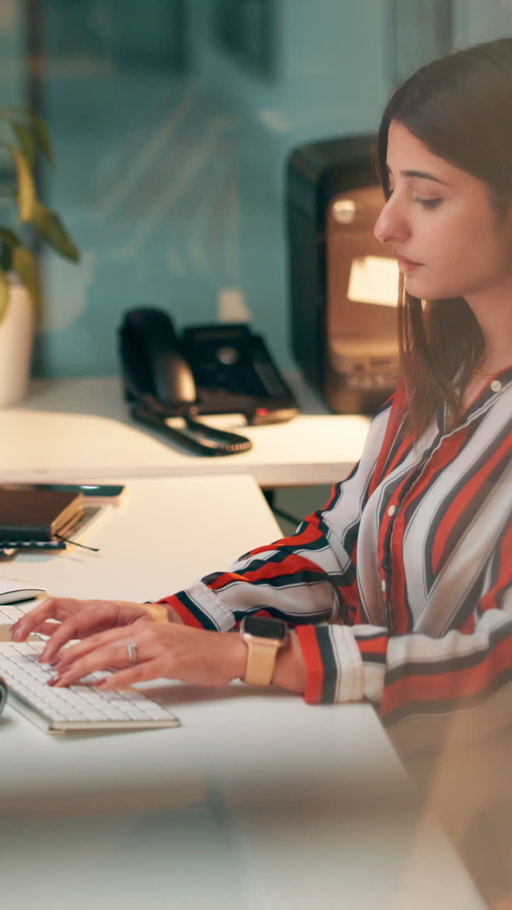 Giovane Donna che Digita sulla Tastiera in un Ufficio Moderno.
