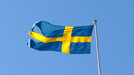 close up of swedish flag waving on windy and sunny day