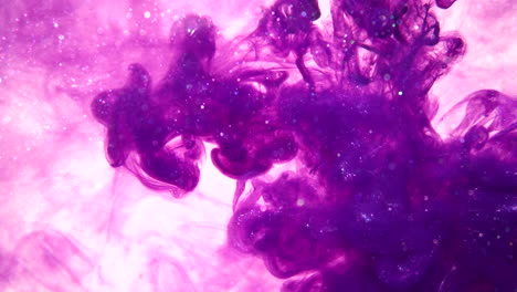 purple ink drops in slow motion flowing in water making a smokey colorful abstract background