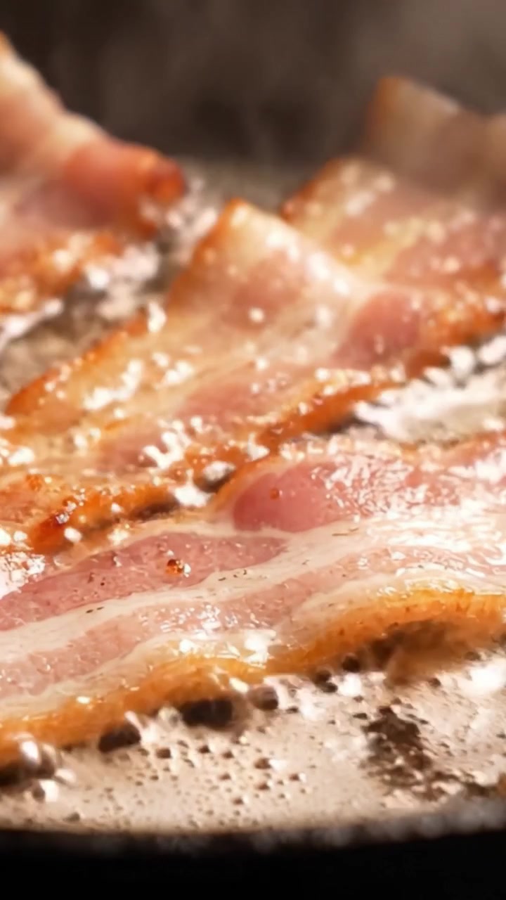 Spruttende bacon steger på en pande: Udforskning af den sprøde tekstur og velsmagende smag i kunsten at stege lækre strimler til morgenmad eller madlavningsentusiaster.