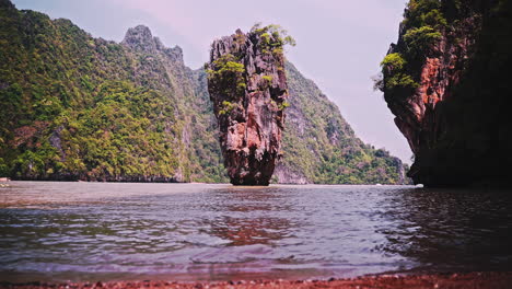 rock pillar formation close to shore in sea bay with cliffs, thailand