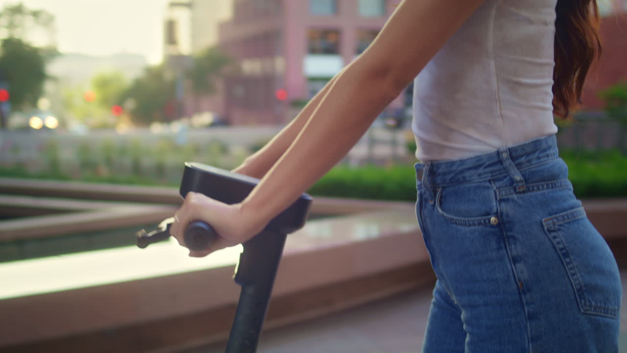 귀여운 소녀는 전기 자전거를 이용해 건축물을 지켜보고 있습니다. 아시아 여자가 스쿠터를 타고 운전합니다.