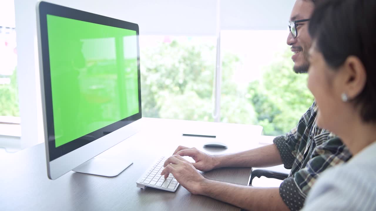 reunión de negocios. pequeña discusión de grupo de inicio en la habitación. joven asiático presentando a su equipo su idea en una computadora de pantalla verde. nuevo modelo de negocio comenzar conceptos.