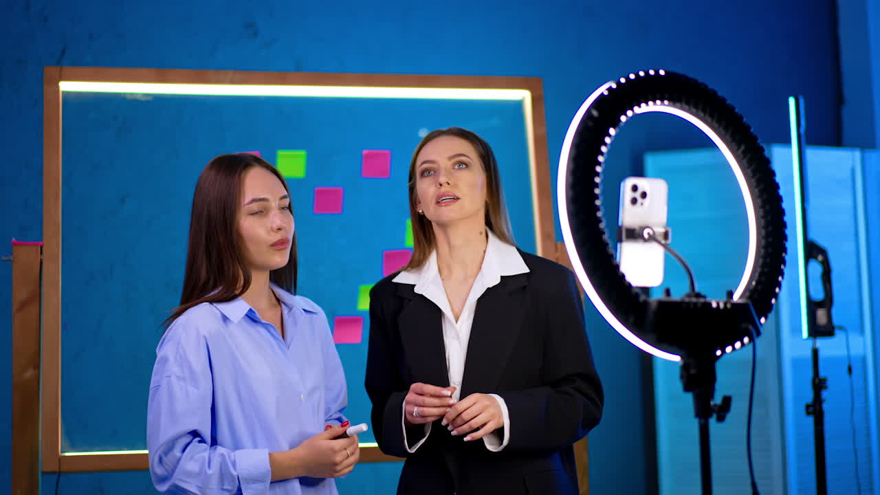 Young women making studio content. Two young women engage in a creative discussion while recording in a bright studio filled with colorful notes