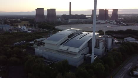 Aerial-view-orbiting-solar-rooftop-industrial-company-and-fossil-fuel-power-station-on-British-sunrise-skyline