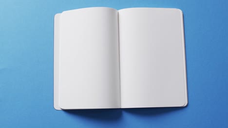 close up of open blank book with copy space on blue background in slow motion