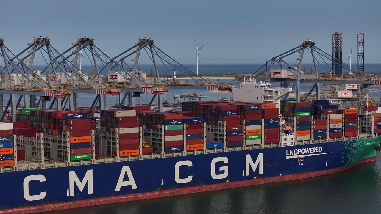 Container ship unloading cargo at a busy port terminal with cranes towering over the vessel