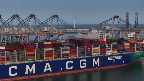 container ship unloading cargo at a busy port terminal with cranes towering over the vessel