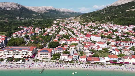 aerial drone view of baška beach, krk island, croatia - valley, town, mountains, tourists and blue sea at a summer sunny day