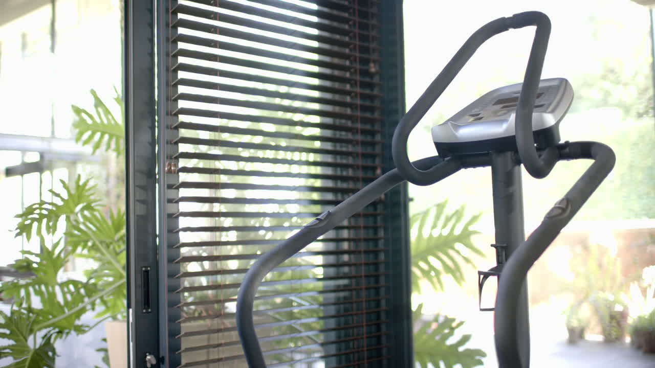 Treadmill standing by window in sunny home gym, slow motion