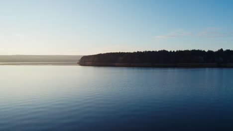 flying over blue water in the evening. beautiful calm river on trees background in nature at sunset. motion camera forward.