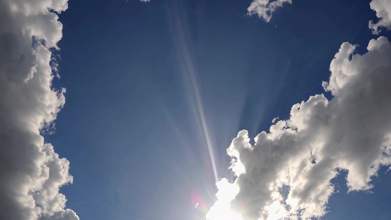 Rayos de sol brillando a través de nubes blancas en el cielo azul