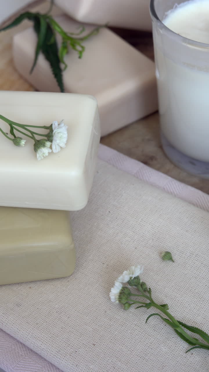 Close up of white candles and soaps on a wooden surface. Vertical