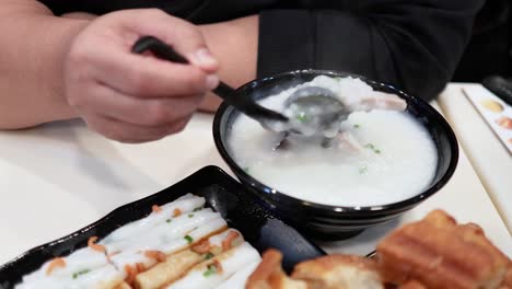 person eating congee with dough sticks in hong kong