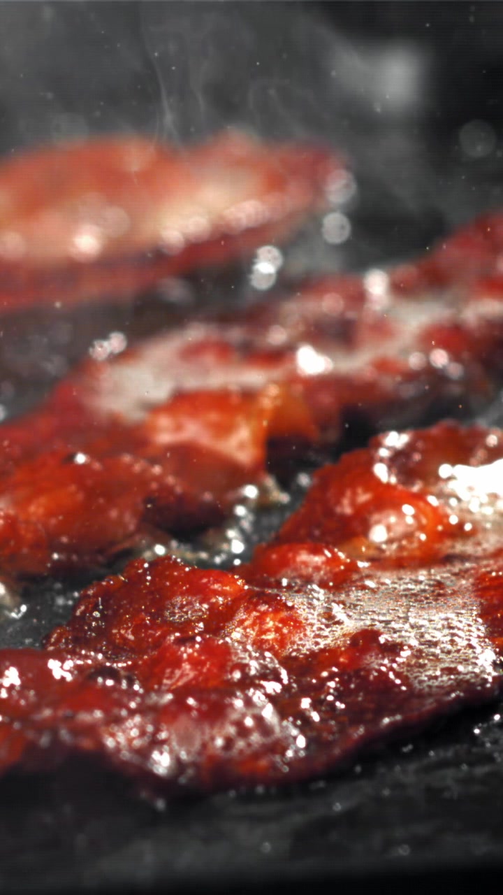 Primo piano di pancetta sfrigolante che frigge in una padella calda.