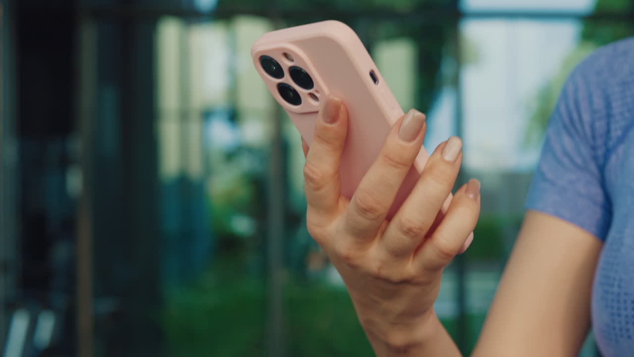 Woman holding a pink phone in a gym