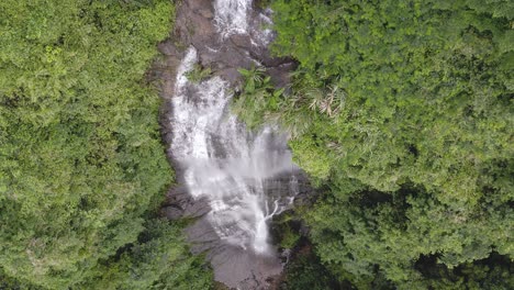 amazing waterfall cascading over forest precipice, 4k aerial top down view
