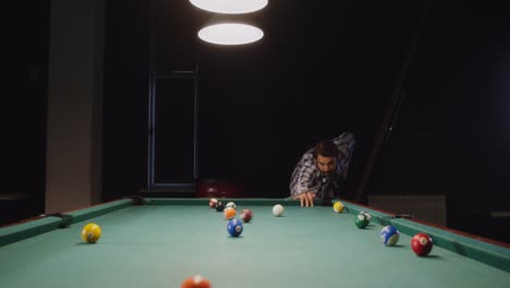 hombre jugando al billar en una habitación oscura