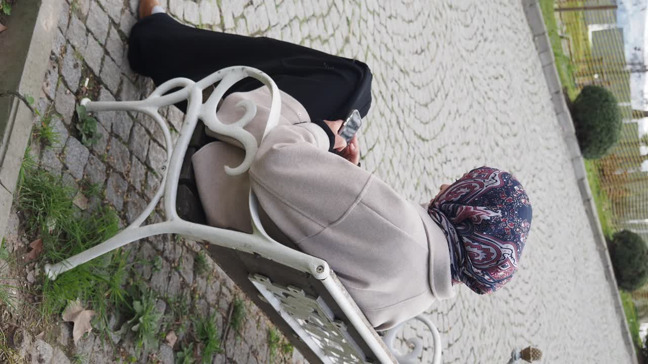 Woman sitting on a park bench using a mobile phone