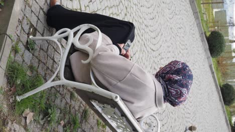 woman sitting on a park bench using a mobile phone