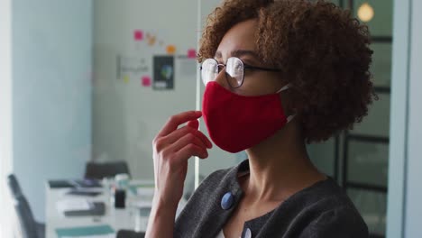 Nachdenkliche-Afroamerikanische-Frau-Mit-Gesichtsmaske-Und-Hand-Am-Kinn-Im-Modernen-Büro