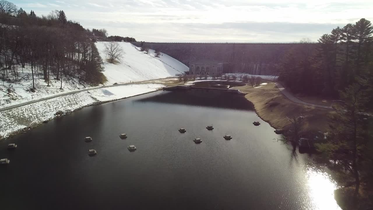 drone acercándose a la presa del embalse de wachusett desde el lado bajo, mirando la fuente decorativa en la base de la presa