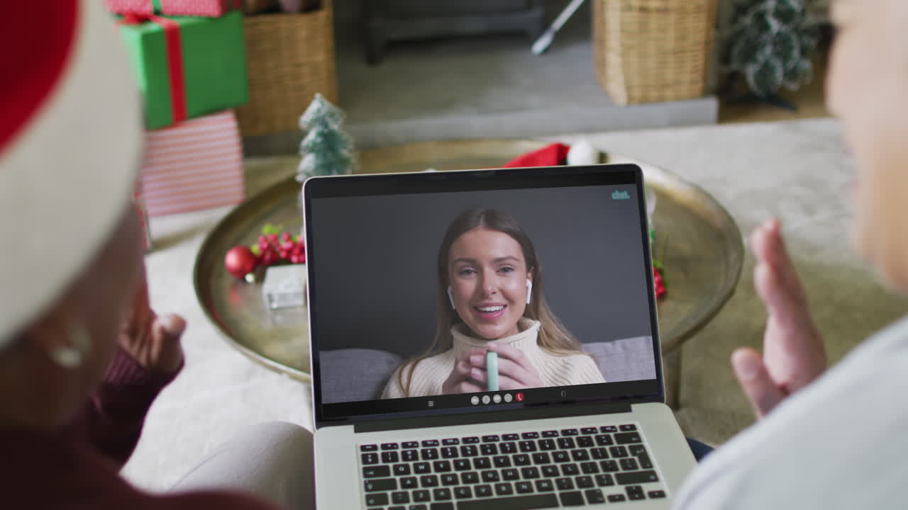 diversas amigas mayores que usan una computadora portátil para una videollamada de navidad con una mujer feliz en la pantalla