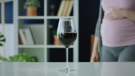 video of pregnant woman grabbing a glass of red wine.