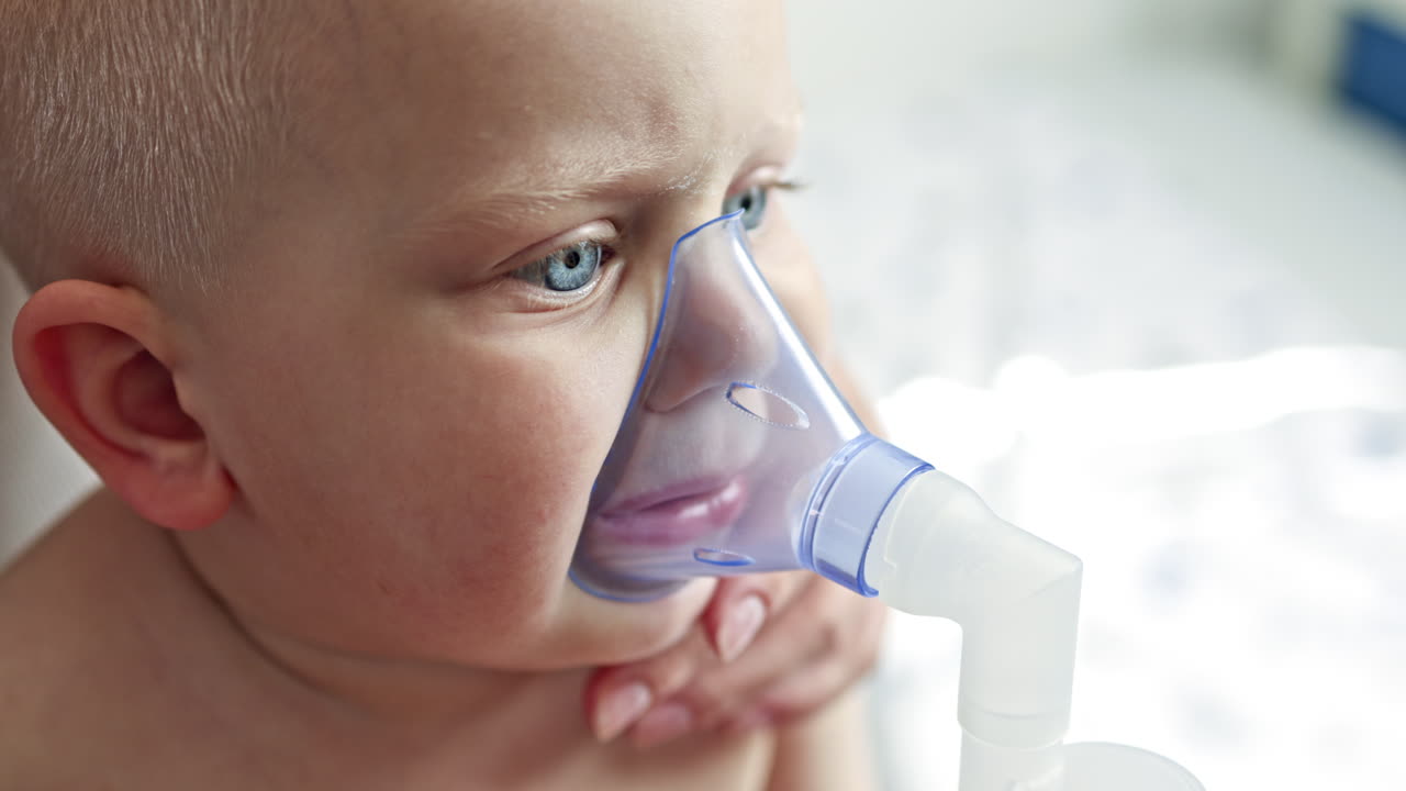 Little boy breathes with an inhaler. Child with a mask on his face breathes with a medical nebulizer. Treatment of a child's cough at home. Inhalation procedure for treating a child
